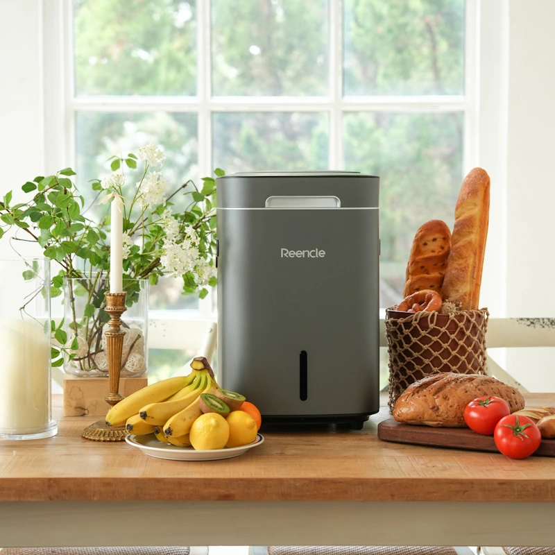 Sivi Reencle Prime komposter na stolu s hranom – elegantno rješenje za kućno kompostiranje bez muke
